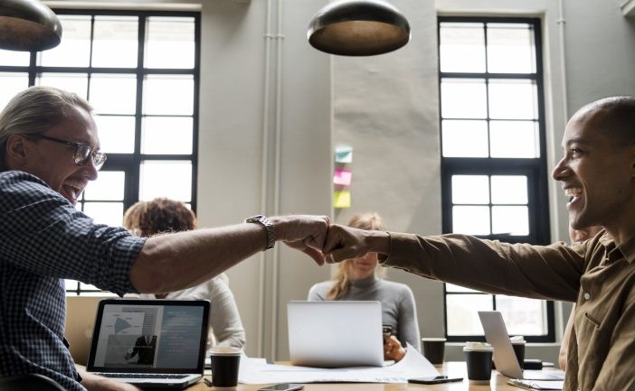 Two contact center employees bump fists in celebration of their positive impact.